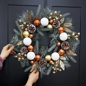 Christmas wreath with artificial pine, gold ornaments, pinecones and fake snow coating