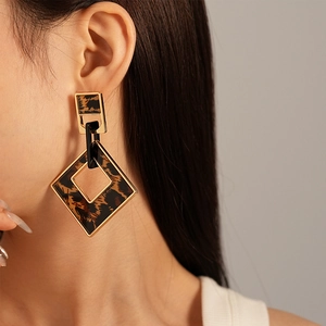 Retro acrylic leopard print geometric earrings with gold trim worn by a female model