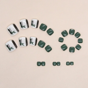 Dark green and white press-on toenails set with leaf patterns and feminism lettering
