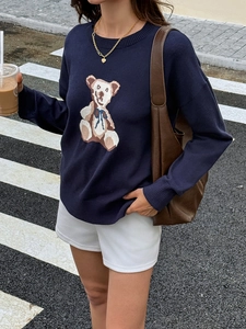 Detail of navy blue knit sweater featuring a teddy bear pattern with a round neckline