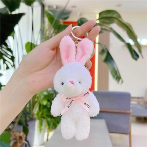 Gros plan d'un porte-clés lapin en peluche blanche avec ruban rose et fermoir doré