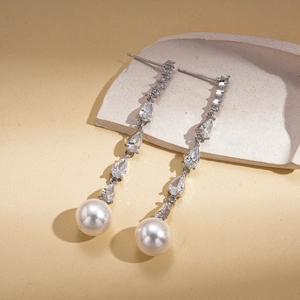 Close-up of elegant drop earrings with silver tassels, sparkling zircons, and white pearls