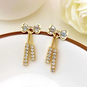 Detalle de pendientes de lazo dorado con circonitas y borlas colgantes con pavé de diamantes