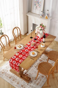 Detail of red Christmas table runner with festive pastry prints on a wooden dining table