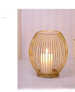 Close-up of golden oval wire cage candle holder with a lit white pillar candle