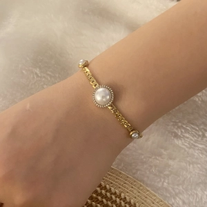 Elegant gold Cuban chain bracelet with pearls and shimmering pavé crystals on a soft background