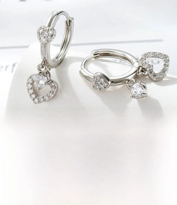 Detail of silver heart hoop earrings with cubic zirconia inlay and hollow heart charms