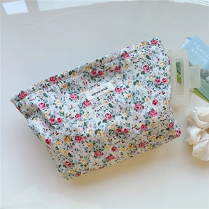 Close-up of floral cotton toiletry bag with simple wish label on a white surface