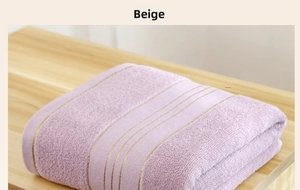 Detail of folded thick cotton bath towel in beige with elegant gold stripe pattern