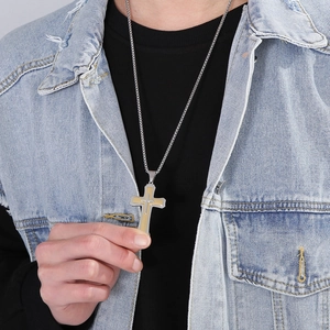 Détail du pendentif croix bicolore argent et or porté par un homme avec une chaîne en métal