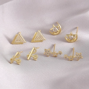 Minimalist gold stud earring set with triangle and star moon designs on silk fabric