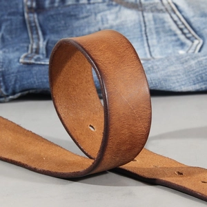 Vintage brown genuine leather belt with antique copper buckle on blue denim jeans background
