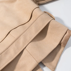 Detail of faux suede jacket belt and textured fabric stitching on a camel blazer