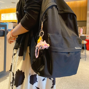 Pink pig cartoon car keychain hanging on a black backpack with golden metal chain