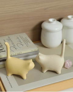 Close-up of minimalist matte ceramic cat figurines in cream and yellow colors