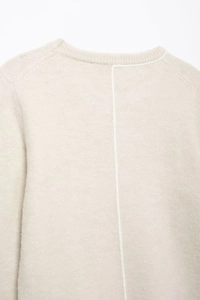 Close-up of beige knit sweater showing soft wool texture and white back seam detail