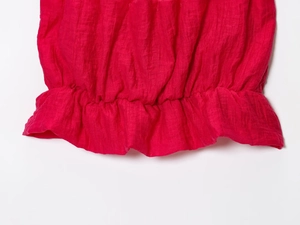 Vue détaillée de la texture du tissu plissé rouge et de l'ourlet à volants de la jupe