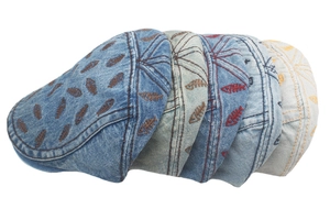 Close-up of washed denim beret hats with detailed fishbone embroidery in multiple colors