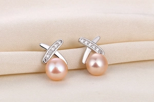 Detailed shot of pink pearl earrings with X-shaped diamond-set cross and silver finish