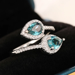 Classic silver bypass ring with pear-shaped blue stones and sparkling diamond halo