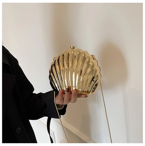 Detail of a metallic gold shell clutch bag featuring a sleek polished surface and chain strap