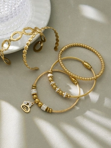 Détails macro de bracelets en acier plaqué or 18k avec zircons et pendentif Love