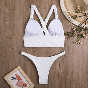 Detailed flat lay of white two-piece bikini with cross straps and wave textured fabric