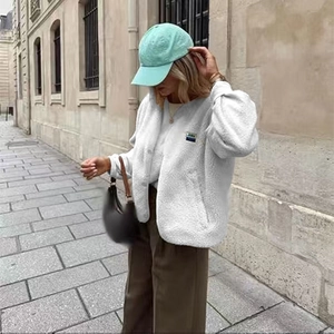 Street style view of a white fleece vest with a small blue chest tag and front buttons
