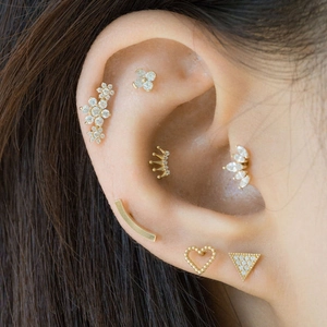 Close-up of S925 silver gold-plated ear piercings with CZ stones and pearl on ear cartilage