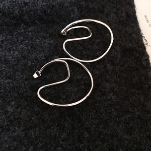 Macro shot of silver minimalist geometric ear clips on a dark plush background