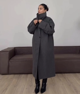 Full view of long dark grey oversized wool coat with lapel collar on a model