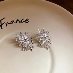 Elegant silver starburst stud earrings with shiny rhinestones in a ceramic tray