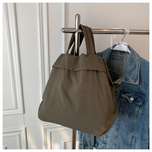 Close-up of lightweight olive nylon tote bag with matte texture and minimalist handles