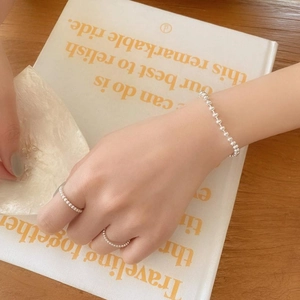 Close-up of minimalist S925 sterling silver beaded bracelet and ring set on model