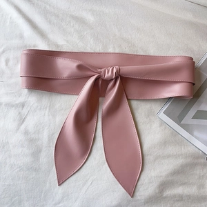 Détail d'une large ceinture rose en cuir PU avec un nœud papillon élégant sur tissu