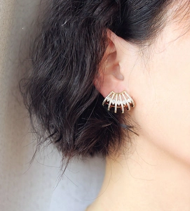 Detail of fan-shaped gold earrings with zircon crystals worn by a female model