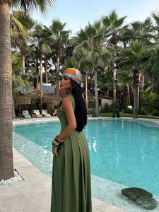 Detailed view of an olive green pleated maxi dress worn by a model at a tropical resort
