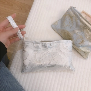 Close-up of floral jacquard embroidery fabric on mini canvas pouch with zipper strap