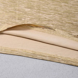 Dettaglio del tessuto in maglia dorata metallizzata con cuciture su fodera beige
