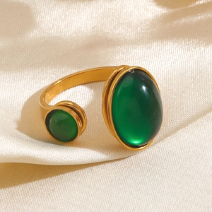 Minimalist gold stainless steel open ring with dual emerald green stones on white silk