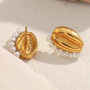 Golden shell-shaped stud earrings with white pearl accents on minimalist textured surface