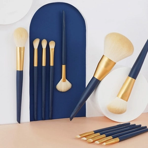 Set of 11 makeup brushes with blue handles and gold ferrules on professional display