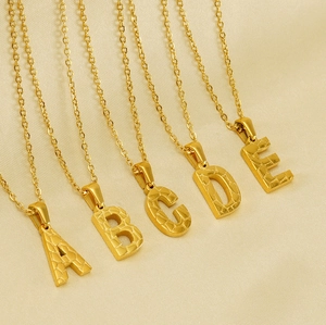 Detailed macro view of 18K gold-plated stainless steel necklaces with textured letter pendants