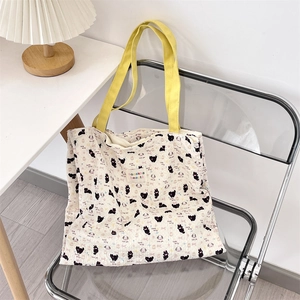 Close-up of cute kitty canvas tote bag featuring yellow straps and artistic heart patterns