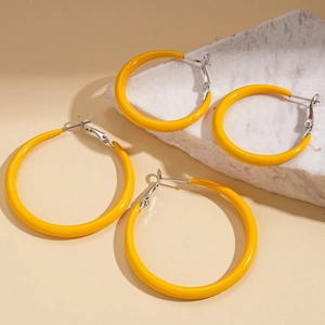 Minimalist yellow enamel hoop earrings set displayed on white marble stone