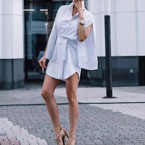 Detailed view of white shirt dress featuring elegant belted waist and cape-style sleeves
