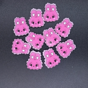 Flat lay of 10 pink resin rabbit head charms with heart ears for DIY phone case crafts