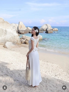 Outdoor shot of a woman in a white square-neck crop top and long skirt set on a beach