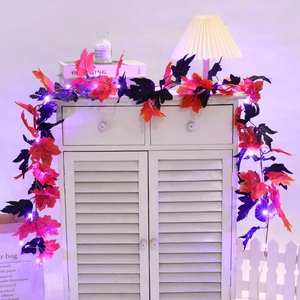 Detail of LED maple leaf garland with warm purple lights on a white shutter cabinet