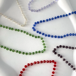 Multicolor faceted crystal bead necklace collection on a white textured tray